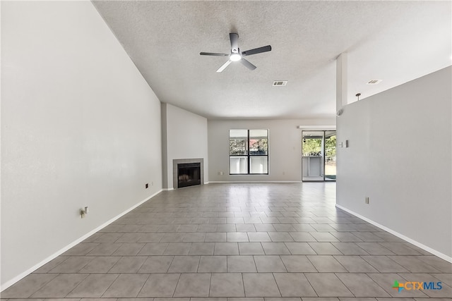 unfurnished living room with a fireplace, a textured ceiling, ceiling fan, and tile patterned flooring