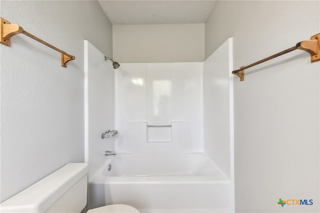 bathroom with washtub / shower combination, a textured ceiling, and toilet