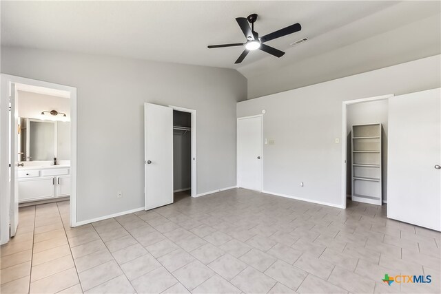 unfurnished bedroom featuring ceiling fan, a spacious closet, ensuite bathroom, vaulted ceiling, and a closet