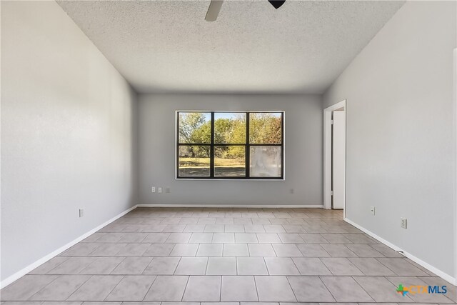 tiled empty room featuring ceiling fan and a textured ceiling