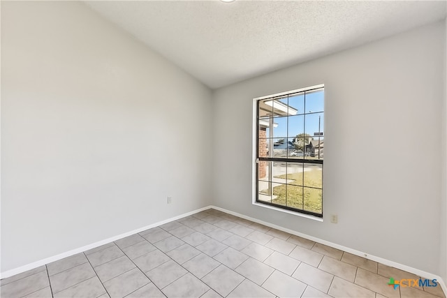 tiled empty room with a wealth of natural light and a textured ceiling