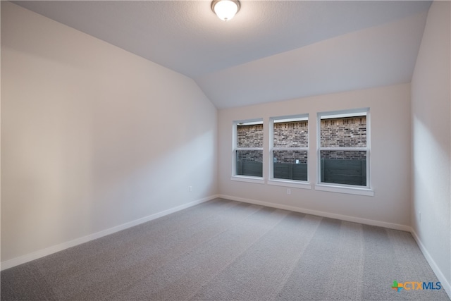 empty room with vaulted ceiling and carpet