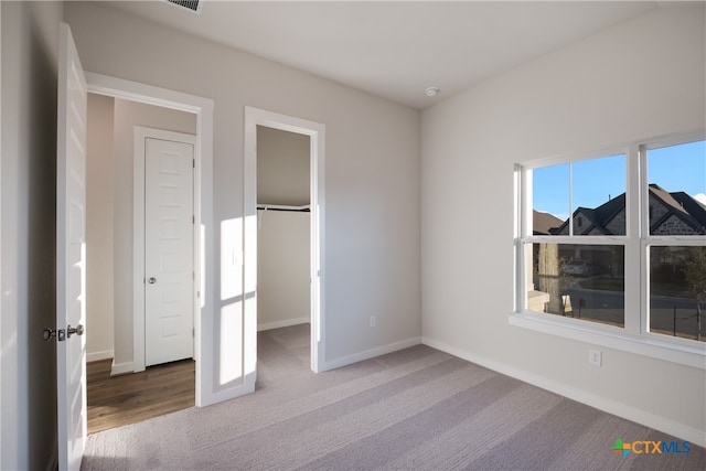 unfurnished bedroom with a closet, a spacious closet, and carpet