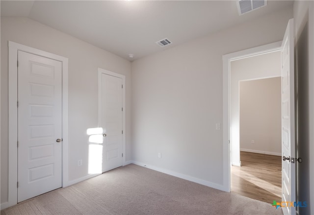 unfurnished bedroom with light colored carpet and vaulted ceiling