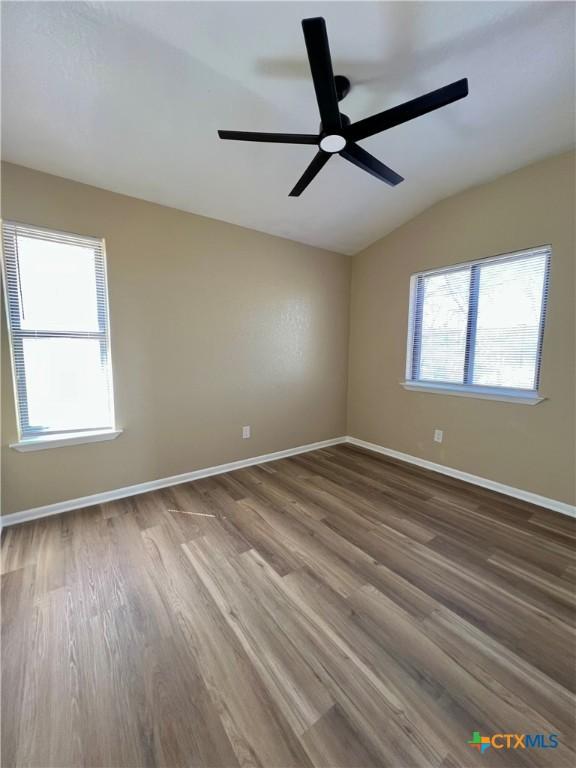 unfurnished room with lofted ceiling, baseboards, and wood finished floors