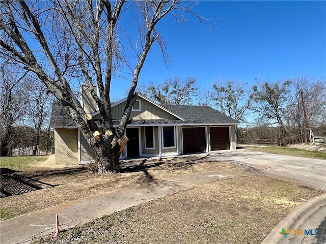 view of front of home featuring roof with shingles, driveway, a chimney, and an attached garage