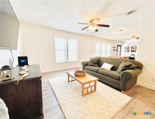 living room featuring a textured ceiling, ceiling fan, and light hardwood / wood-style flooring