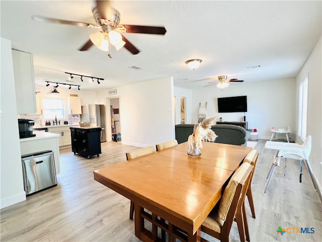 dining room featuring a textured ceiling, ceiling fan, and light hardwood / wood-style flooring