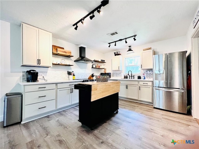 613 E 5th St, Cameron, TX 76520 - kitchen featuring stainless steel fridge, open shelves, exhaust hood, light countertops, and light wood-style floors