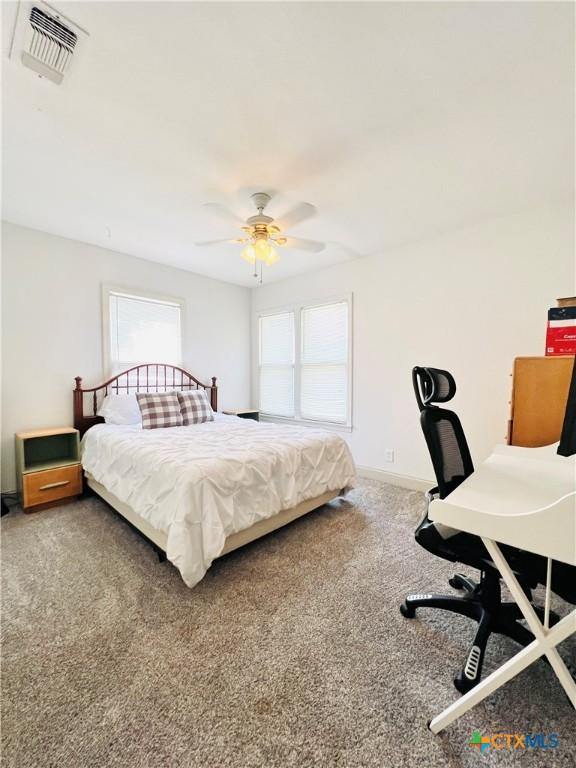 613 E 5th St, Cameron, TX 76520 - carpeted bedroom featuring multiple windows, a ceiling fan, baseboards, and a desk