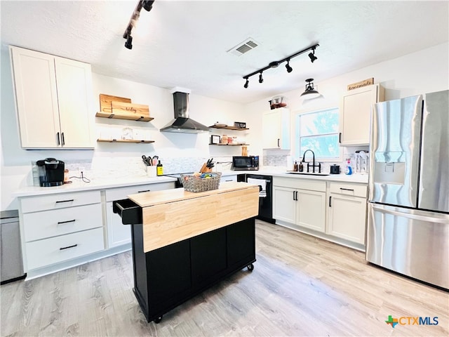 kitchen featuring stainless steel appliances, sink, wall chimney exhaust hood, light hardwood / wood-style flooring, and white cabinets