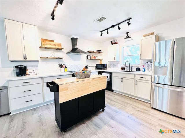 613 E 5th St, Cameron, TX 76520 - kitchen featuring stainless steel fridge with ice dispenser, open shelves, rail lighting, and wall chimney exhaust hood