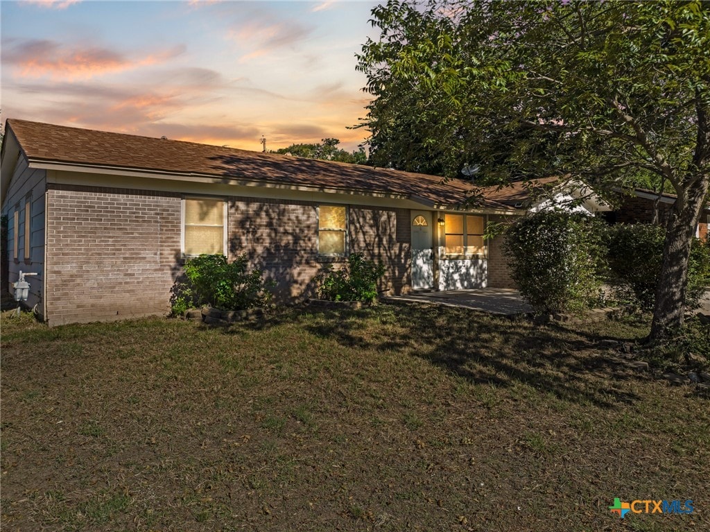 back house at dusk with a lawn