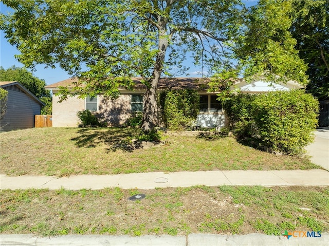 view of property hidden behind natural elements featuring a front lawn