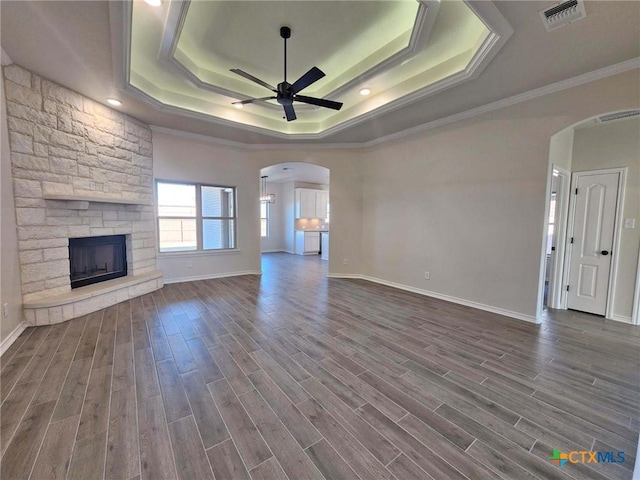 unfurnished living room featuring a fireplace, ornamental molding, a raised ceiling, and ceiling fan