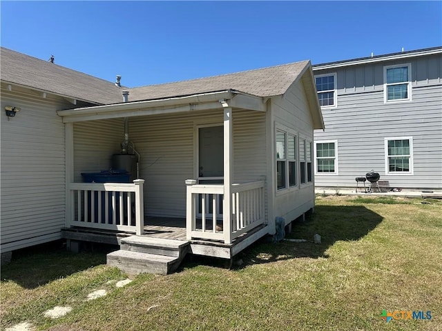 rear view of house featuring board and batten siding, a yard, and a deck