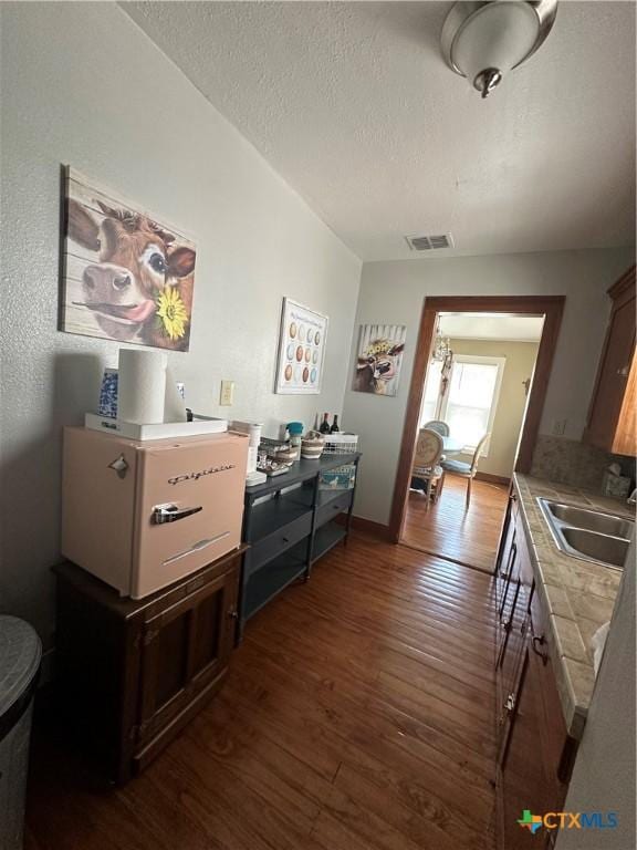 interior space featuring visible vents, a sink, dark wood-style flooring, and a textured ceiling