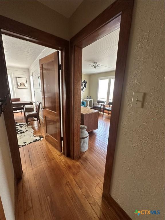 hallway featuring a textured wall and hardwood / wood-style floors