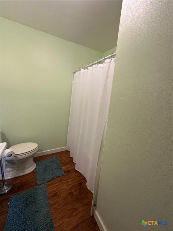full bathroom with toilet, baseboards, and wood finished floors