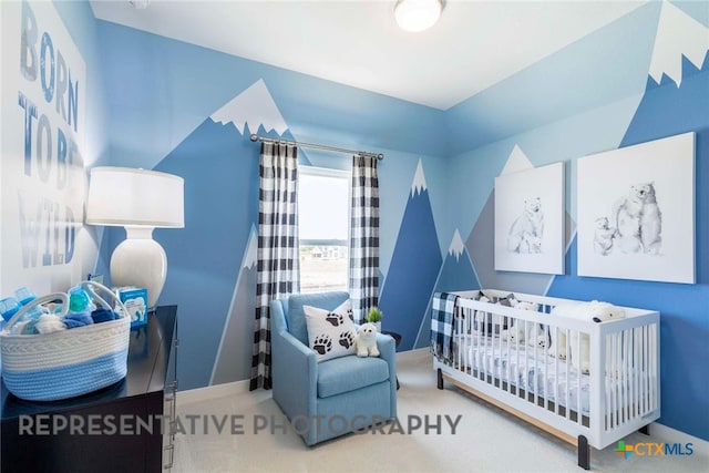 carpeted bedroom featuring a nursery area and baseboards
