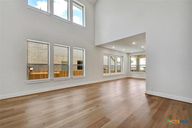 1826 Nettletree Rd, New Braunfels, TX 78132 - unfurnished living room featuring healthy amount of natural light, wood finished floors, and a high ceiling