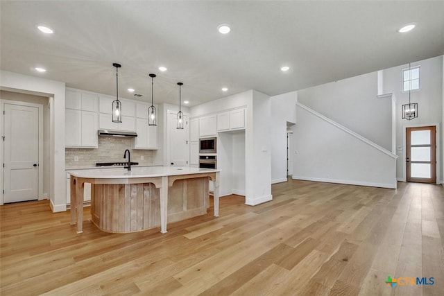 1826 Nettletree Rd, New Braunfels, TX 78132 - kitchen with appliances with stainless steel finishes, light countertops, white cabinets, decorative backsplash, and light wood-type flooring