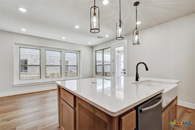 1826 Nettletree Rd, New Braunfels, TX 78132 - kitchen featuring stainless steel dishwasher, light wood finished floors, brown cabinetry, hanging light fixtures, and an island with sink