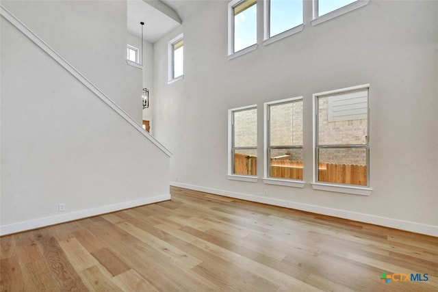 1826 Nettletree Rd, New Braunfels, TX 78132 - unfurnished living room featuring wood finished floors, stairway, and a towering ceiling