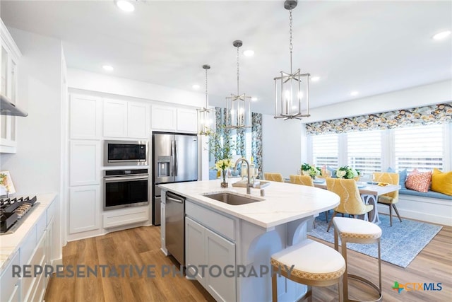 kitchen with stainless steel appliances, a sink, wood finished floors, a chandelier, and recessed lighting