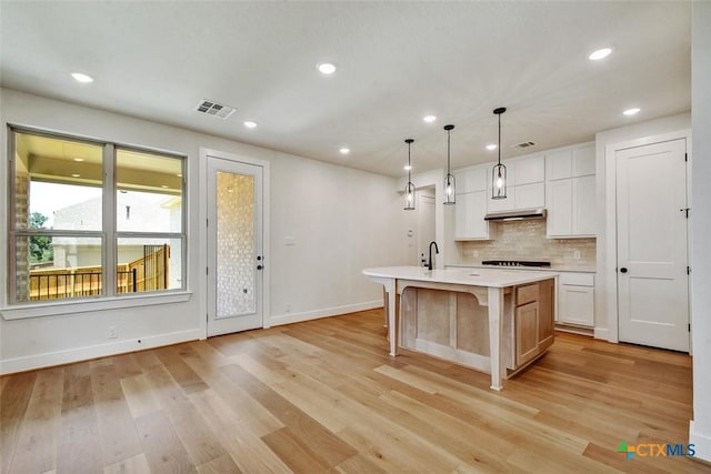 1826 Nettletree Rd, New Braunfels, TX 78132 - kitchen with light countertops, backsplash, a center island with sink, light wood-style floors, and recessed lighting