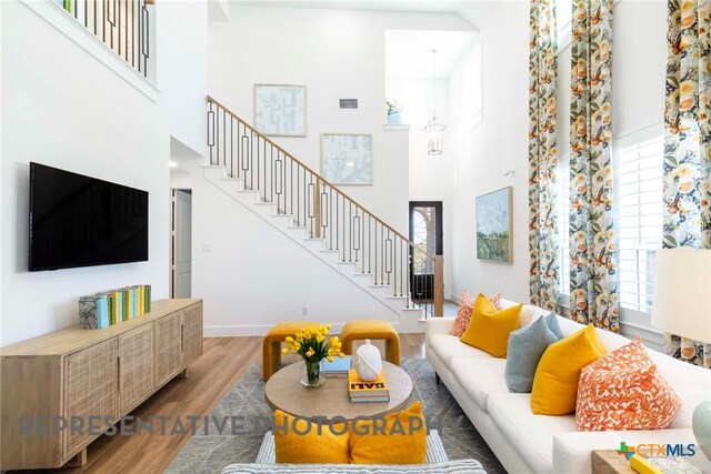 living room featuring a high ceiling, stairs, wood finished floors, and baseboards