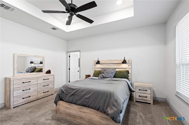 bedroom with ceiling fan, dark carpet, and a raised ceiling