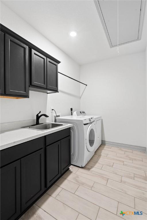 laundry room featuring washing machine and dryer, sink, and cabinets