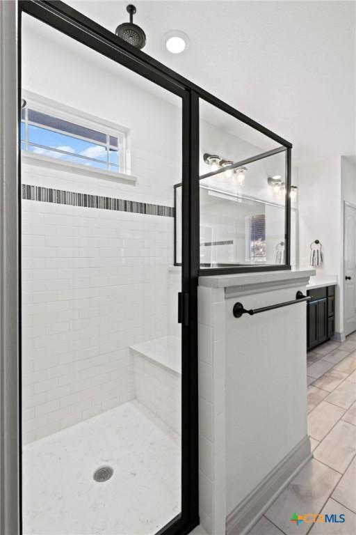 bathroom with tiled shower, vanity, and tile patterned flooring