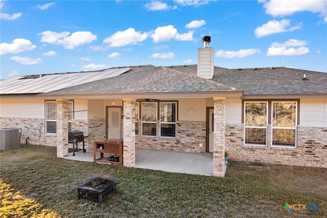 back of property with solar panels, a patio, central AC, and a lawn