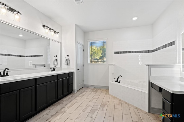 bathroom with vanity and a relaxing tiled tub