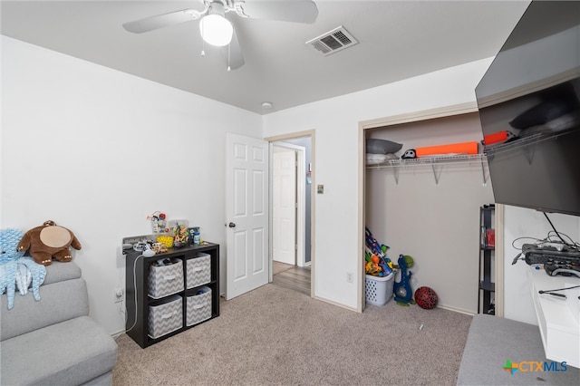 bedroom with ceiling fan, light carpet, and a closet