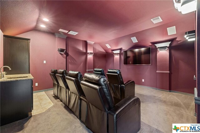 carpeted home theater featuring a textured ceiling, lofted ceiling, sink, and decorative columns