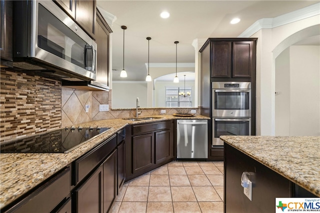 kitchen featuring stainless steel appliances, sink, light stone counters, hanging light fixtures, and crown molding