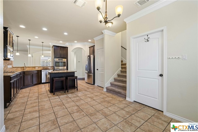 kitchen with stainless steel appliances, crown molding, a kitchen island, a breakfast bar, and pendant lighting