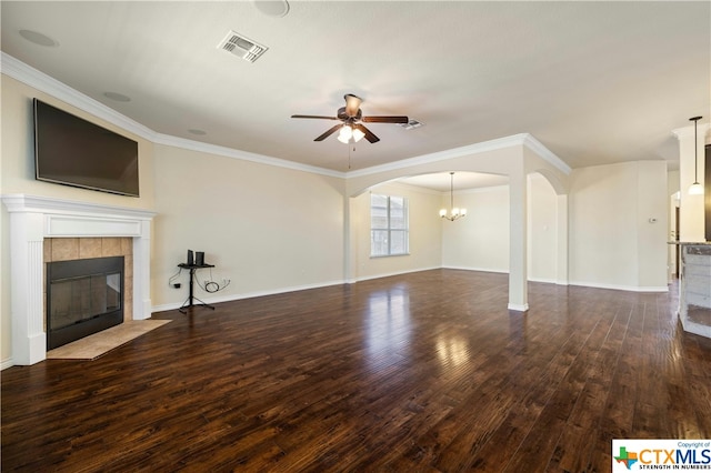 unfurnished living room featuring ceiling fan with notable chandelier, dark hardwood / wood-style flooring, crown molding, and a tile fireplace