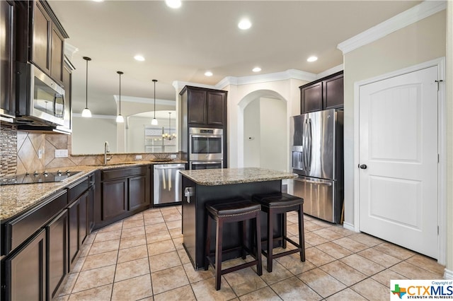 kitchen with stainless steel appliances, decorative backsplash, sink, ornamental molding, and a breakfast bar