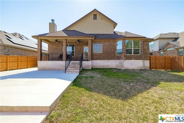 rear view of property featuring ceiling fan, a yard, and a patio area