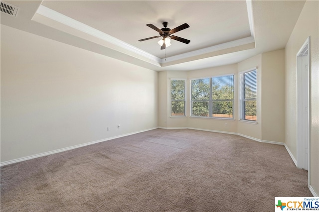 unfurnished room with ceiling fan, carpet flooring, ornamental molding, and a raised ceiling