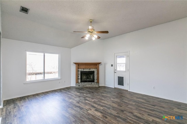 unfurnished living room featuring dark wood-type flooring, lofted ceiling, a textured ceiling, ceiling fan, and a fireplace