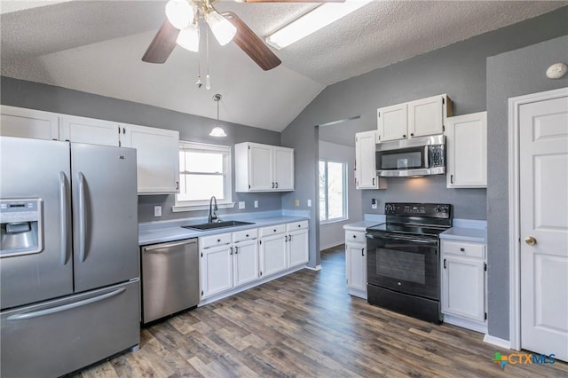 kitchen featuring a sink, white cabinets, light countertops, appliances with stainless steel finishes, and hanging light fixtures