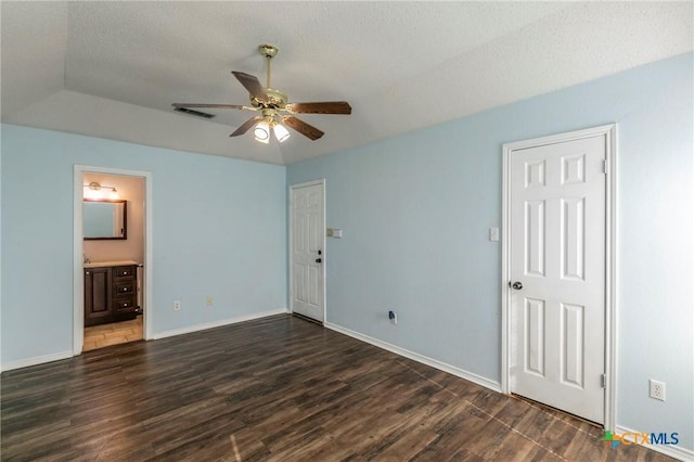 unfurnished bedroom with ceiling fan, dark wood-type flooring, a textured ceiling, and ensuite bathroom