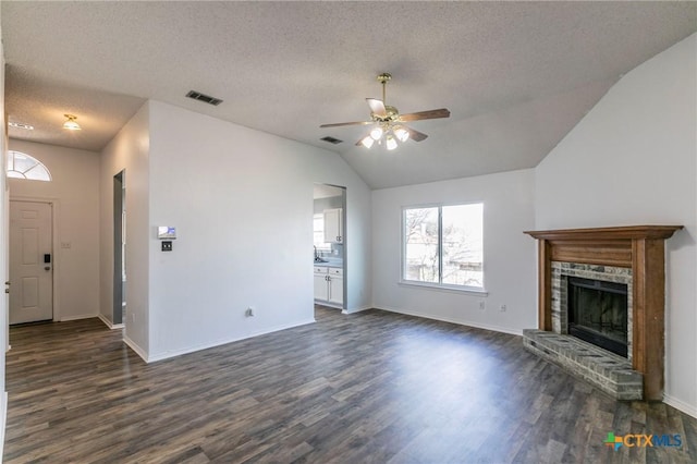 unfurnished living room with a brick fireplace, vaulted ceiling, dark hardwood / wood-style floors, and ceiling fan