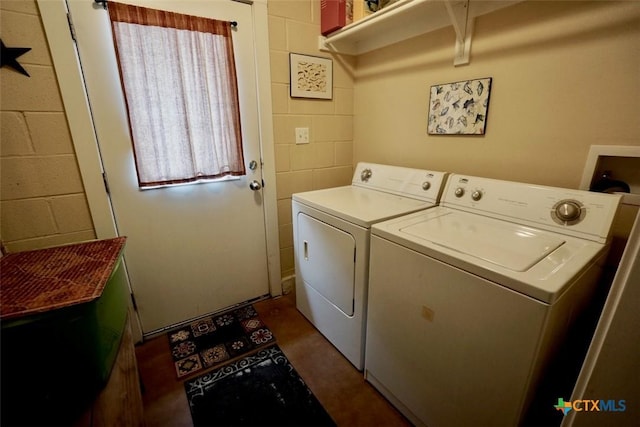 washroom with concrete block wall, plenty of natural light, separate washer and dryer, and laundry area