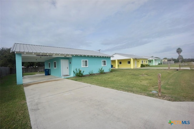 view of front of home with an attached carport, fence, concrete driveway, a front yard, and metal roof